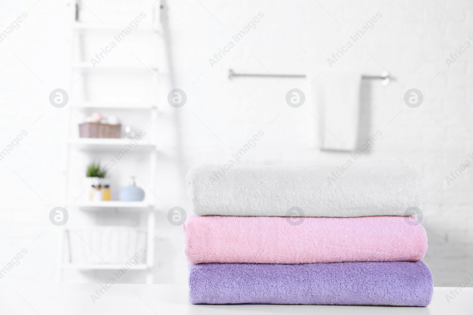 Photo of Stack of fresh towels on table in bathroom. Space for text