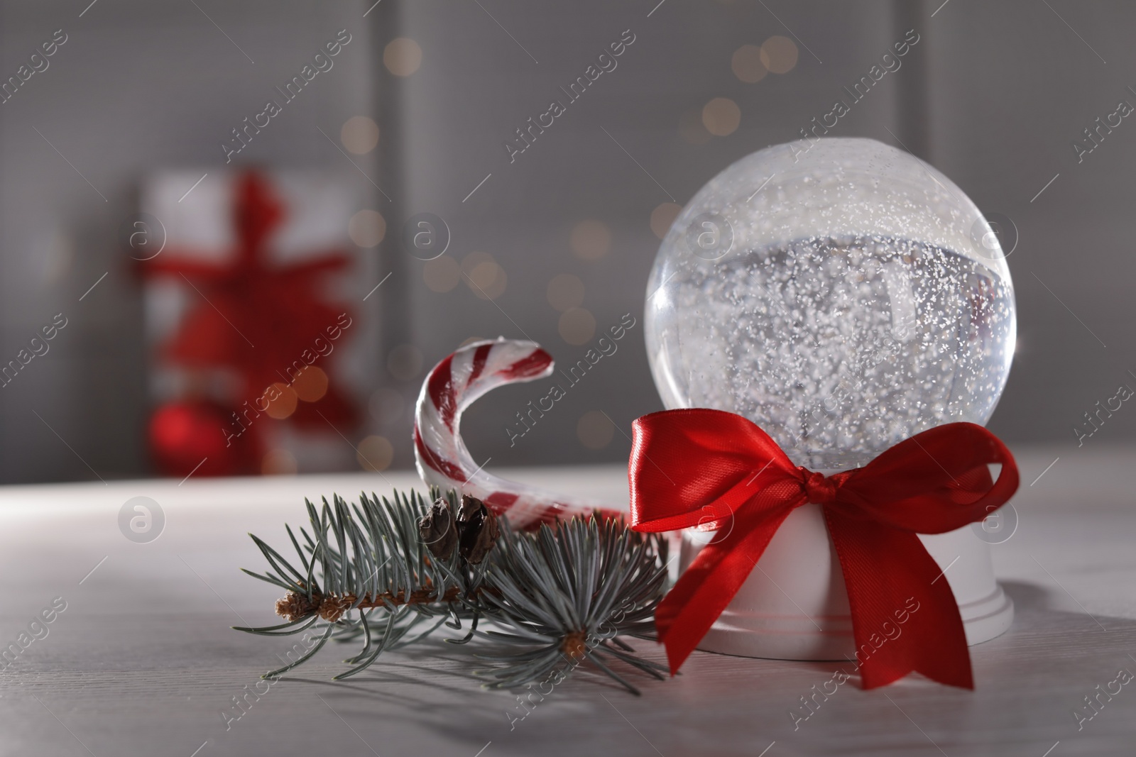 Photo of Christmas snow globe with red bow on table. Space for text