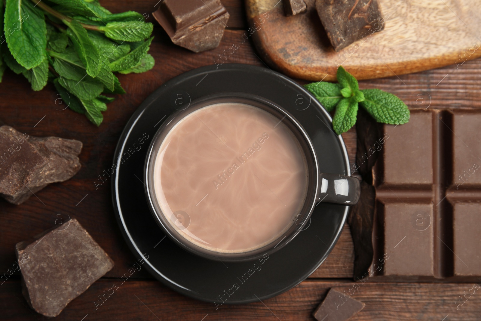 Photo of Cup of delicious hot cocoa, chocolate chunks and fresh mint on wooden table, flat lay