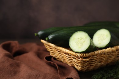 Photo of Fresh cucumbers in wicker basket on table, closeup. Space for text