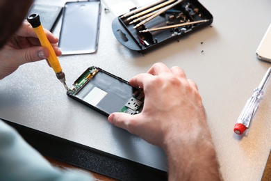 Technician repairing mobile phone at table, closeup