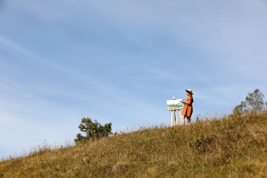 Young woman drawing on hill, space for text