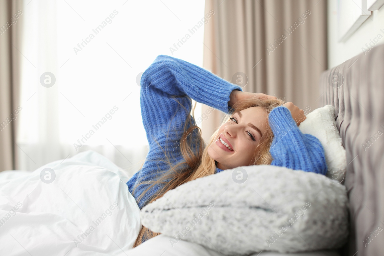 Photo of Beautiful young woman lying in bed at home. Winter atmosphere