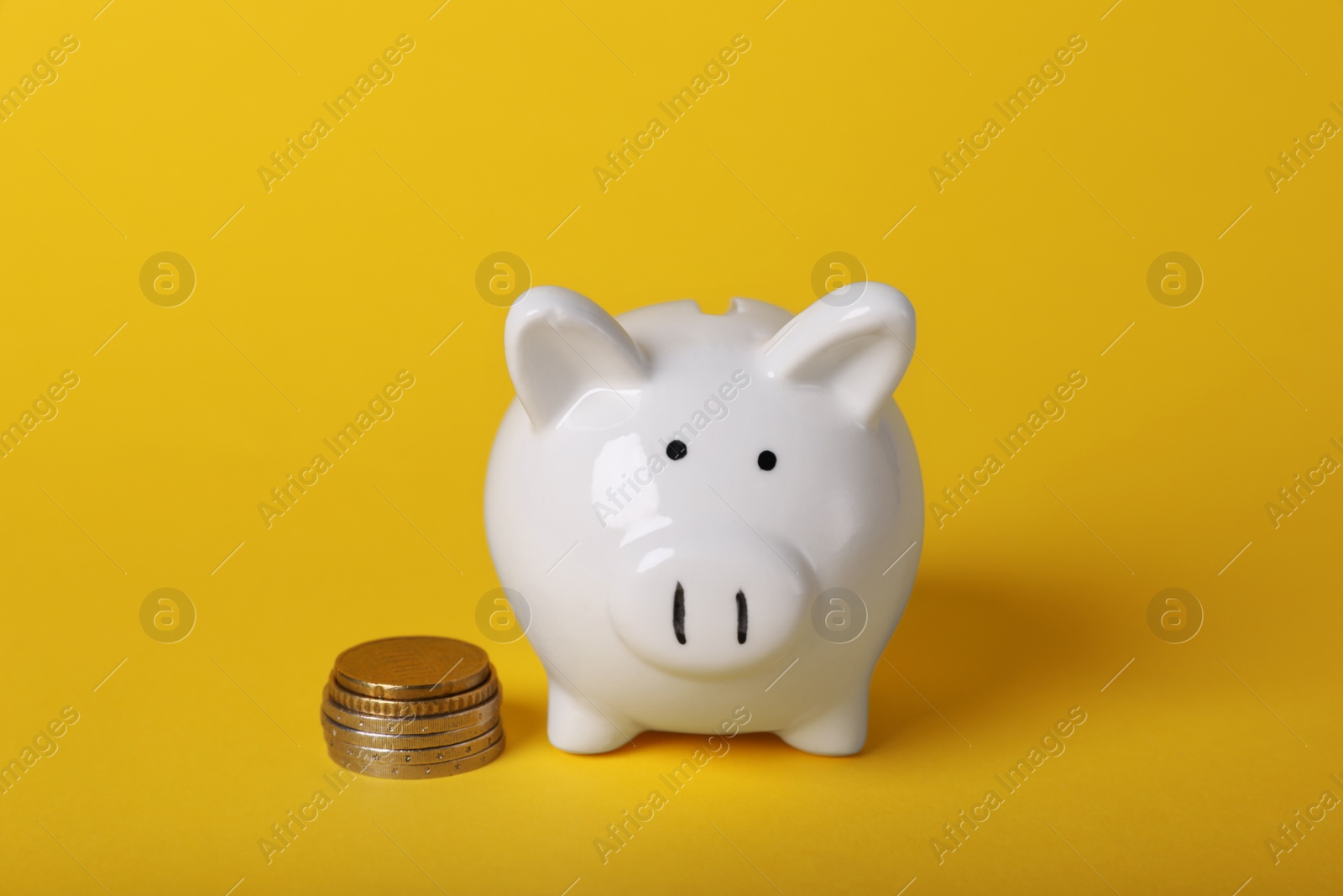 Photo of Ceramic piggy bank and coins on yellow background. Financial savings