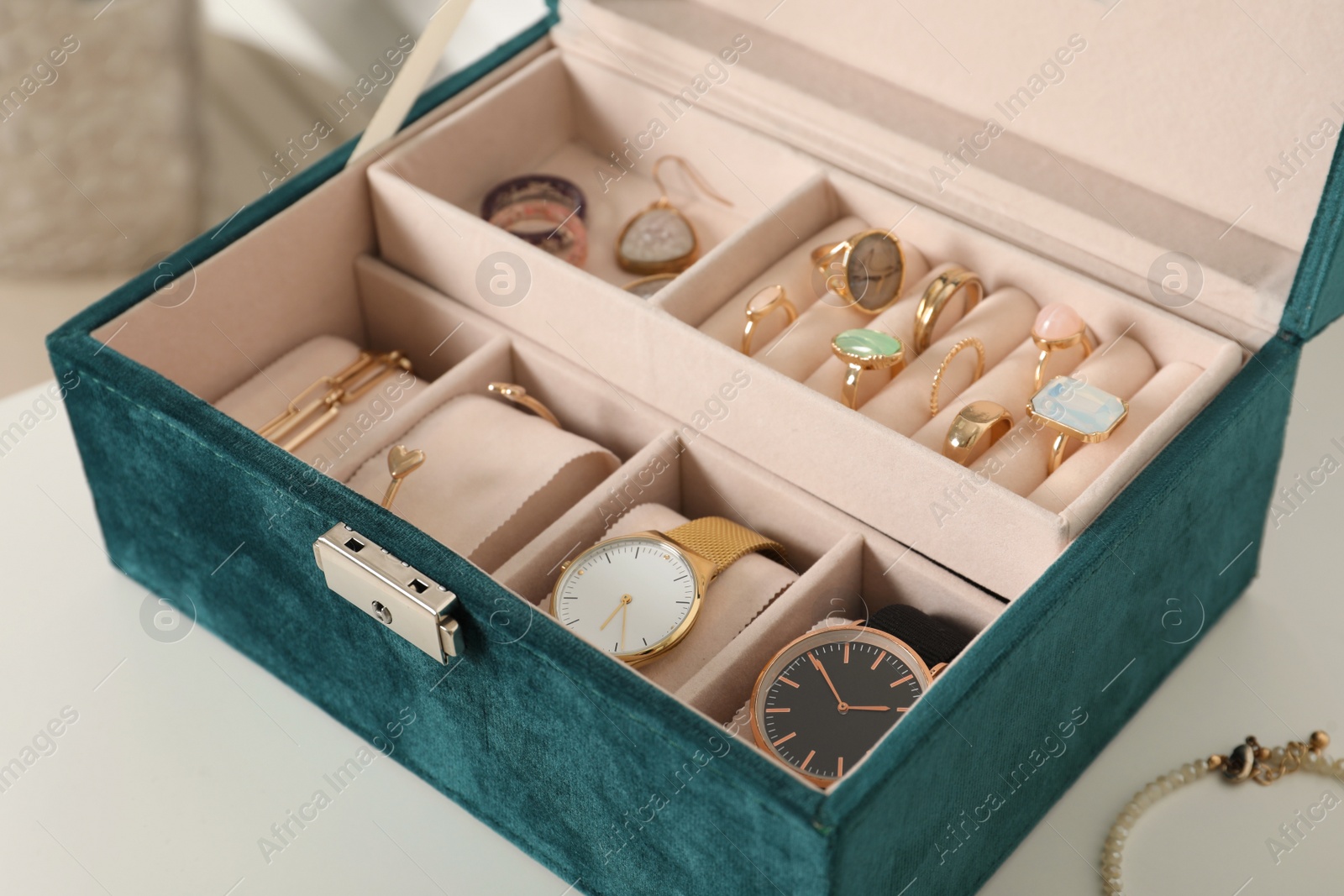 Photo of Elegant jewelry box with beautiful bijouterie and expensive wristwatches on white table, closeup