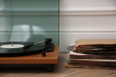 Photo of Stylish turntable with vinyl records on floor indoors