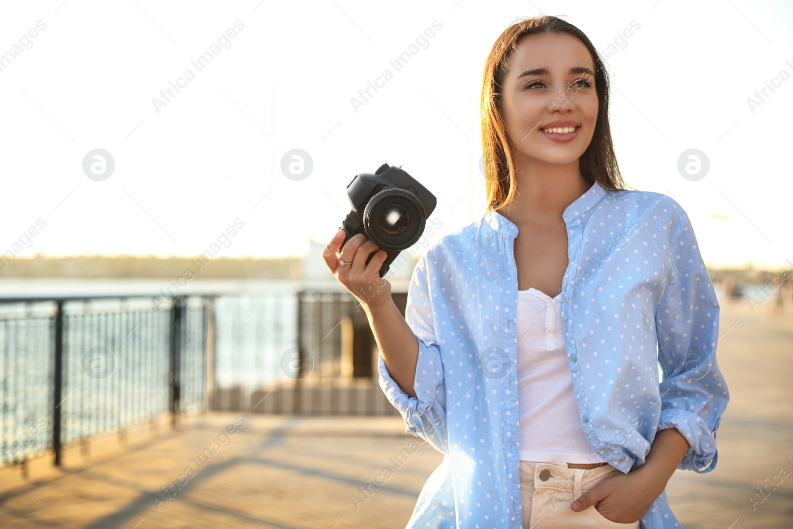 Photo of Young photographer with professional camera outdoors. Space for text