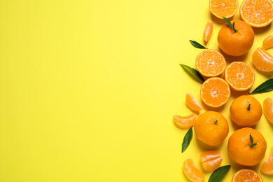 Photo of Flat lay composition with fresh ripe tangerines and leaves on yellow background, space for text. Citrus fruit