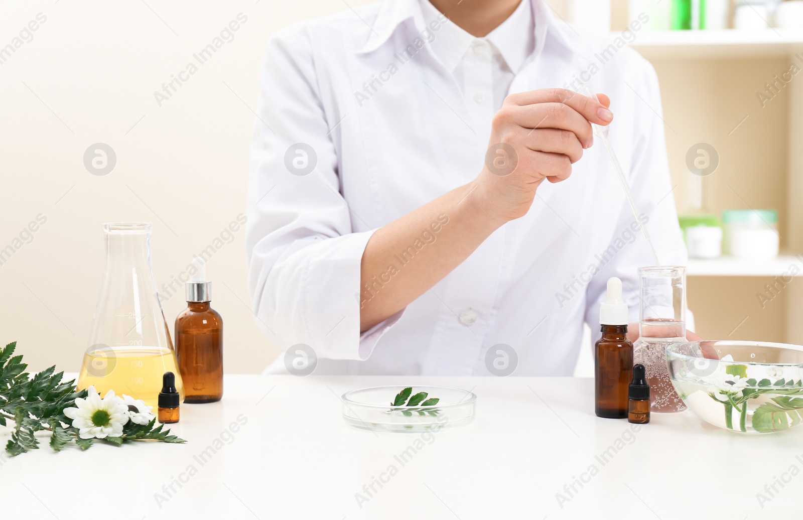 Photo of Female dermatologist creating skin care product at table, closeup