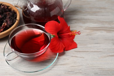 Delicious hibiscus tea and beautiful flower on light wooden table, space for text