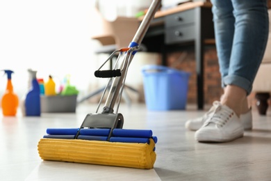 Photo of Woman cleaning floor with mop in living room, closeup
