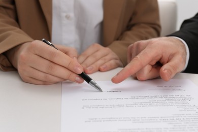 Photo of Businesspeople signing contract at white table, closeup of hands