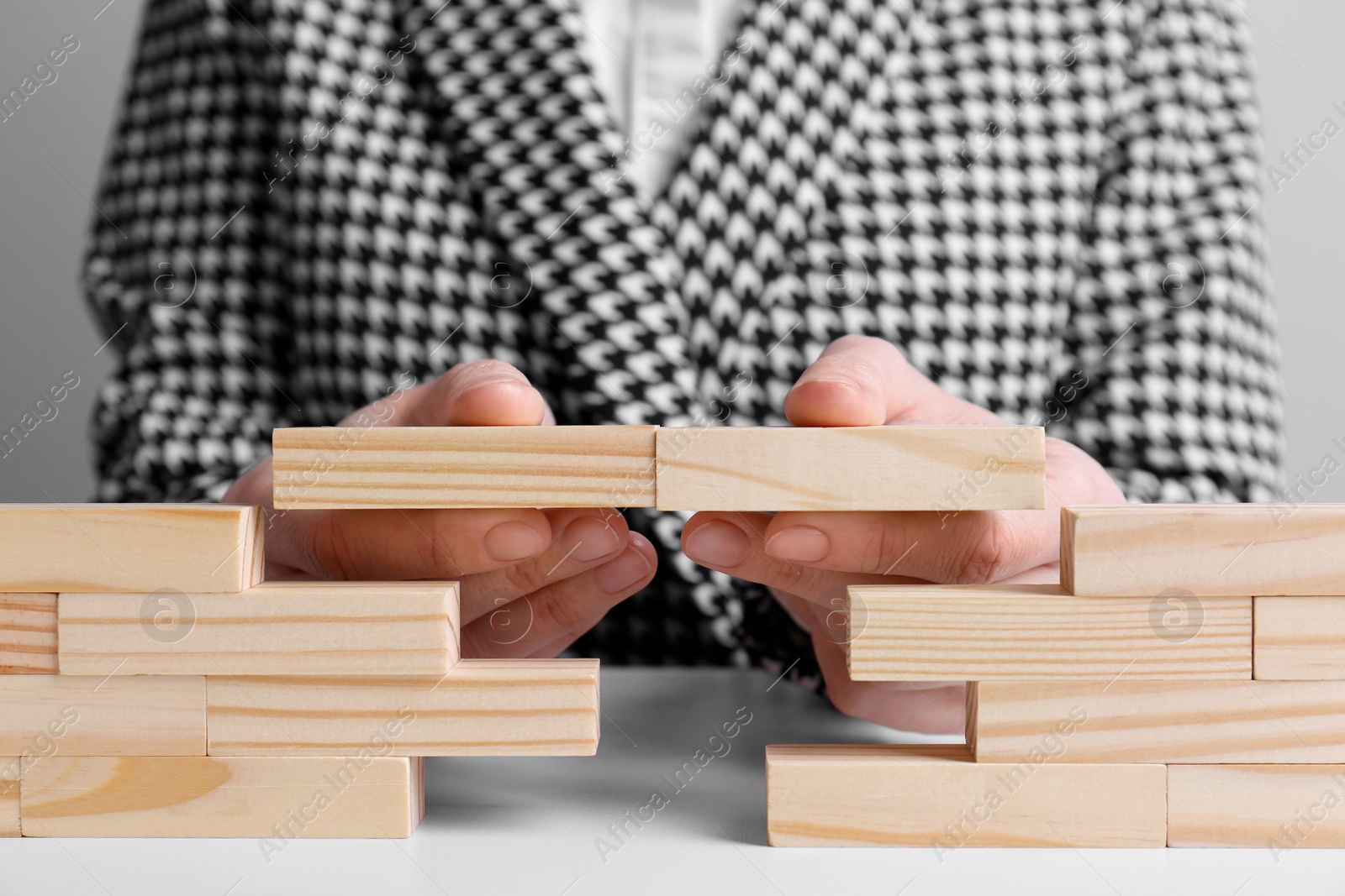 Photo of Businesswoman building bridge with wooden blocks at table, closeup. Connection, relationships and deal concept