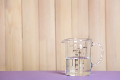 Measuring cup with vinegar on table. Space for text