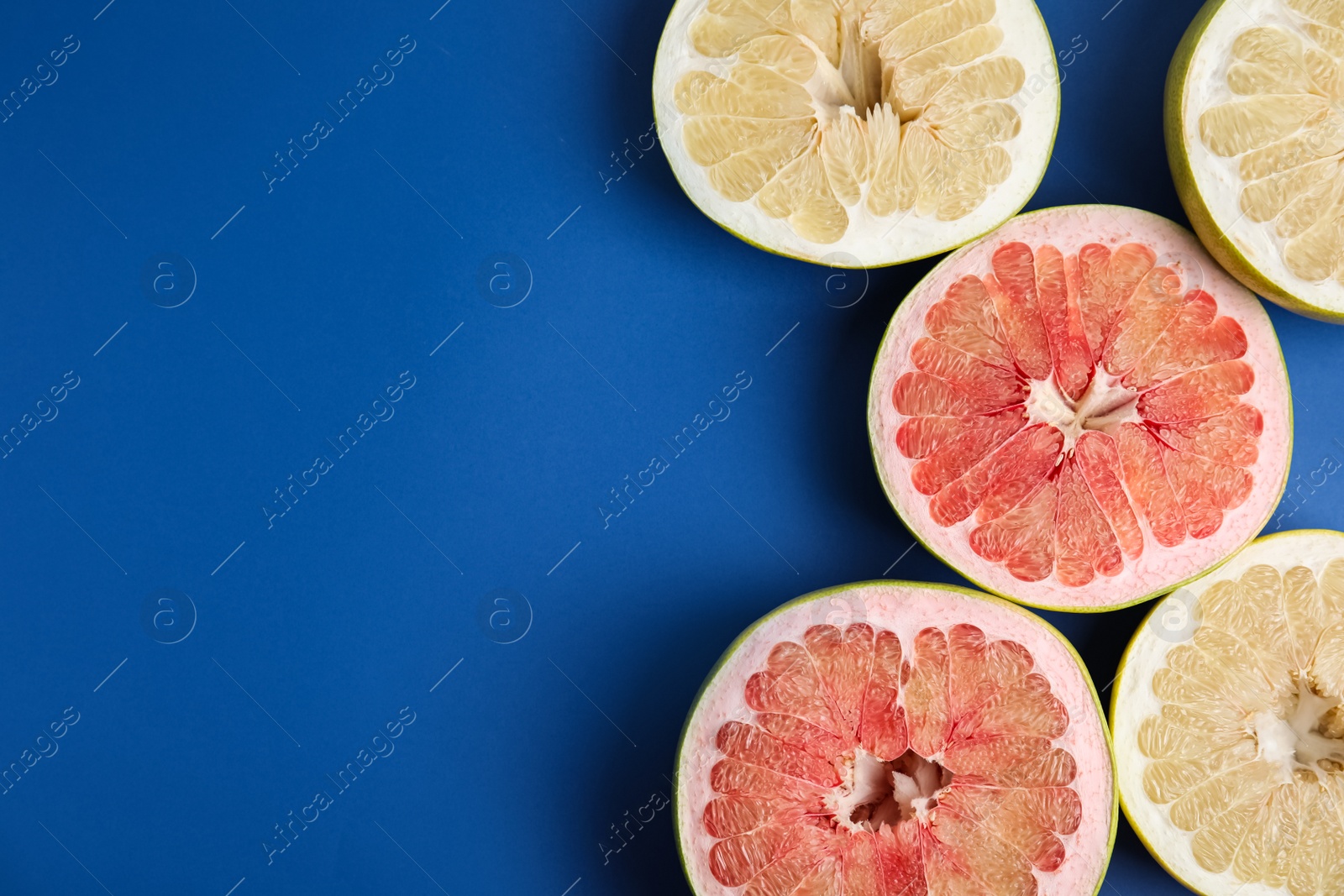 Photo of Fresh cut pomelo fruits on blue background, flat lay. Space for text