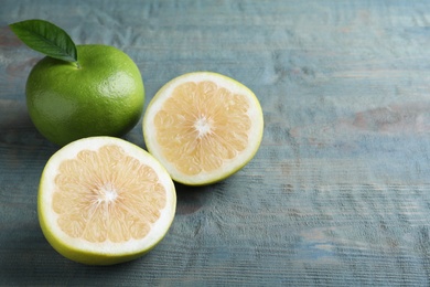 Photo of Whole and cut sweetie fruits on blue wooden table, space for text