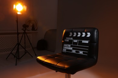 Photo of Casting call. Chair, clapperboard and different equipment in modern studio