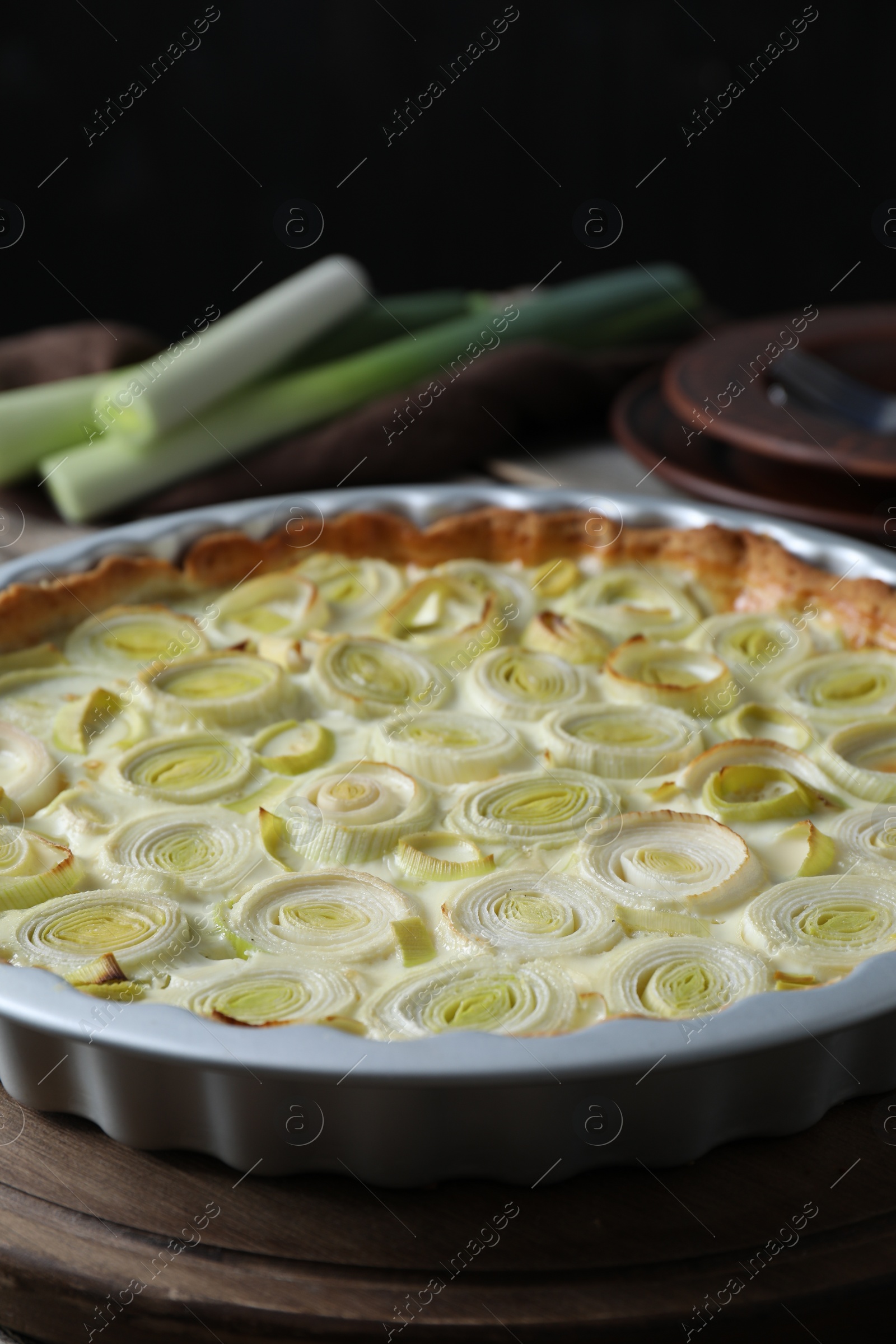 Photo of Tasty leek pie and raw stems on table, closeup