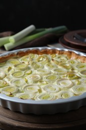 Tasty leek pie and raw stems on table, closeup