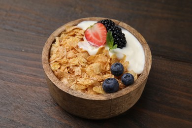 Photo of Delicious crispy cornflakes, yogurt and fresh berries in bowl on wooden table, closeup. Healthy breakfast