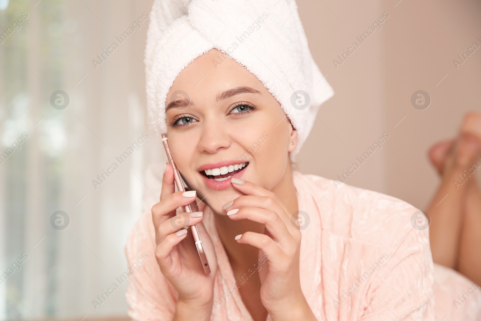 Photo of Beautiful woman with towel on head talking on phone at home