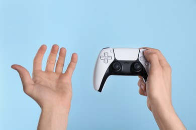 Photo of Man using wireless game controller on light blue background, closeup