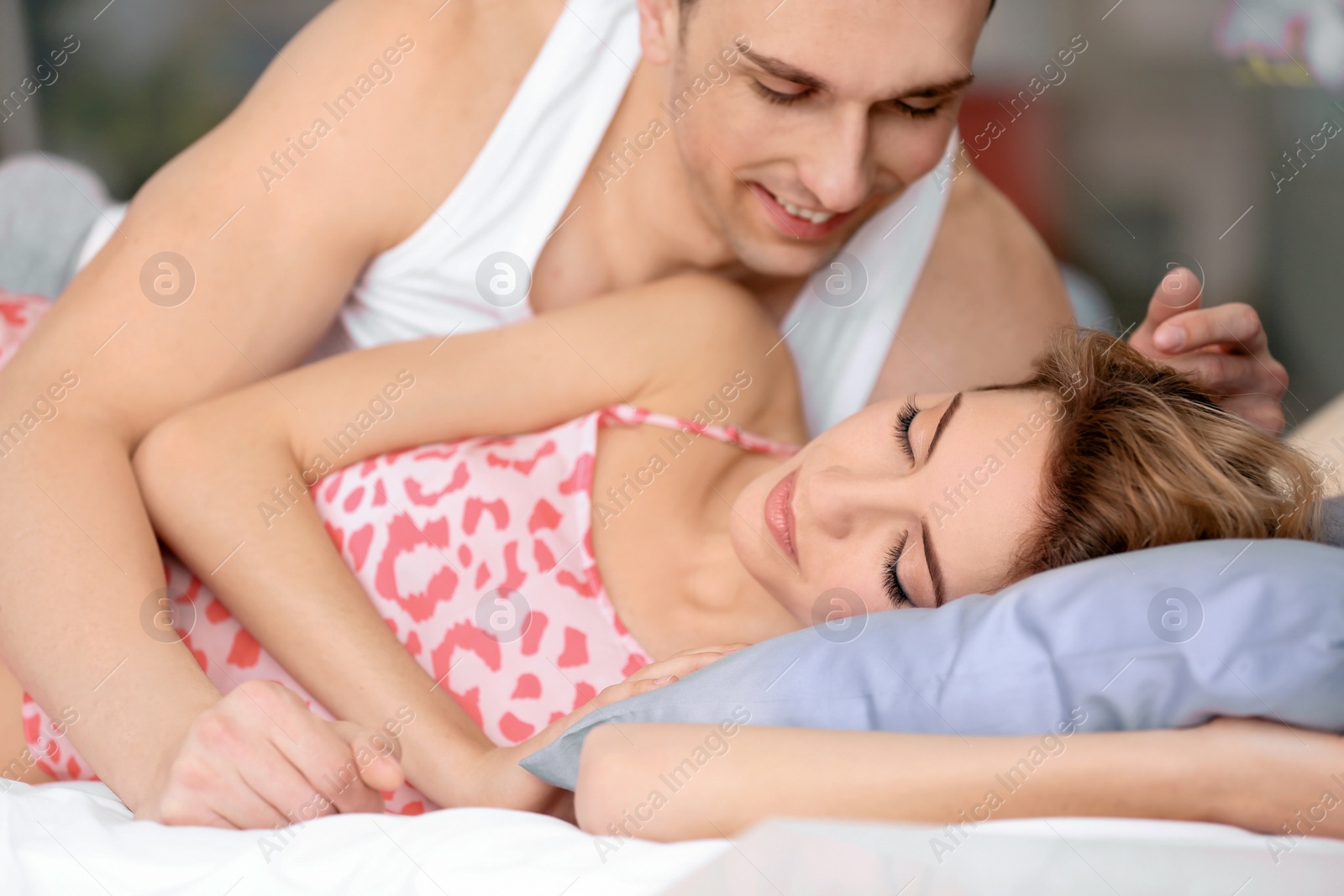 Photo of Young man hugging his girlfriend in bed at home