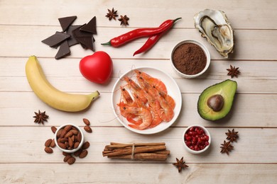 Photo of Natural aphrodisiac. Different food products and red decorative heart on light wooden table, flat lay