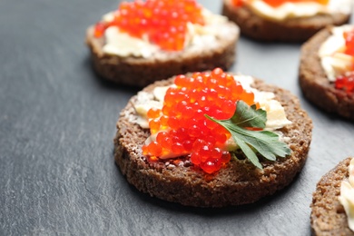 Photo of Delicious sandwiches with red caviar on slate plate