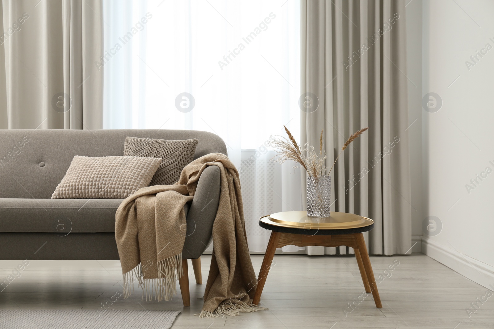 Photo of Grey sofa with pillows near window in stylish living room interior