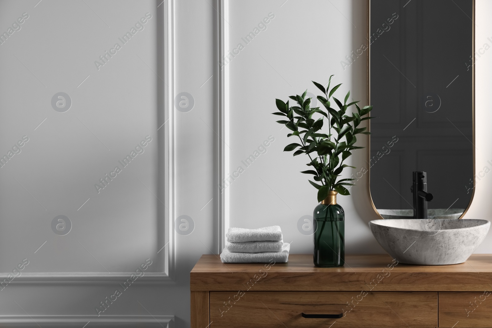 Photo of Eucalyptus branches and folded towels near stylish vessel sink on bathroom vanity, space for text. Interior design