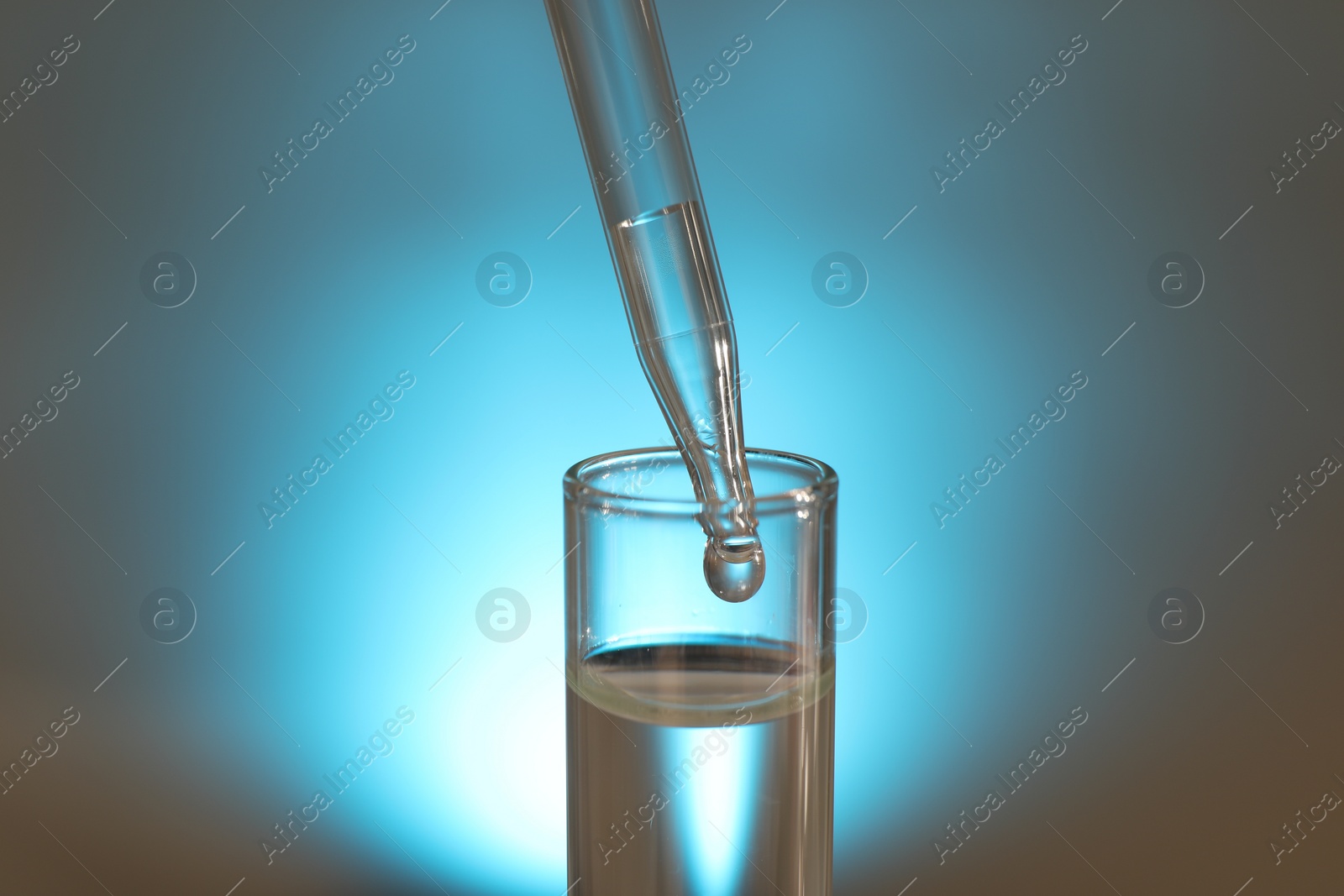 Photo of Dripping liquid from pipette into test tube on light background, closeup