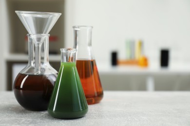 Laboratory glassware with different types of crude oil on light grey table, space for text