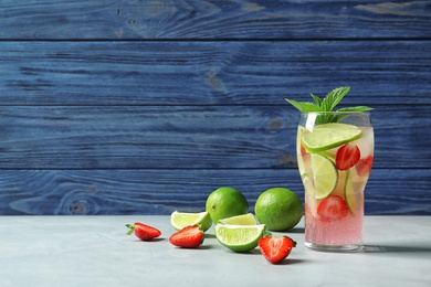 Photo of Natural lemonade with lime and strawberries in glass on table