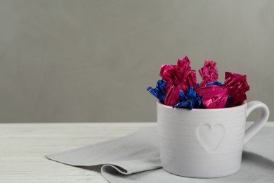 Photo of Candies in colorful wrappers on white wooden table. Space for text