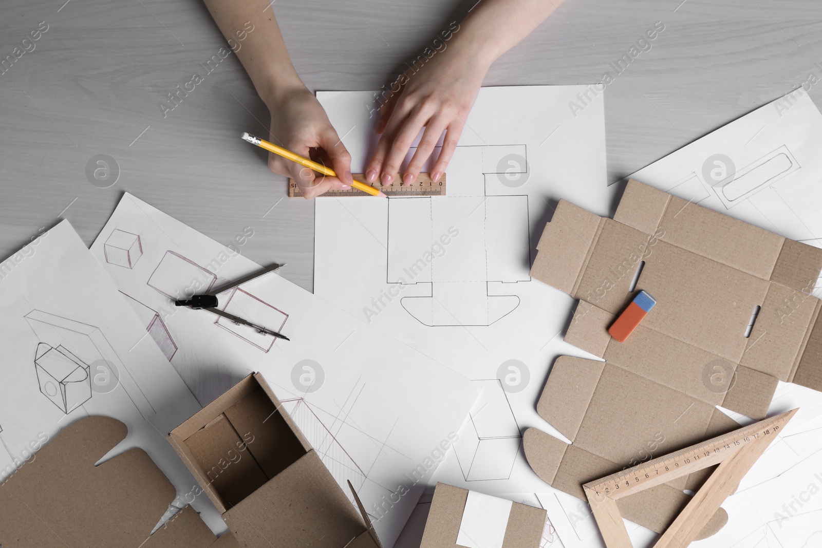 Photo of Woman creating packaging design at light wooden table, top view