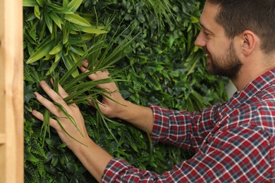 Man installing green artificial plant wall panel, closeup