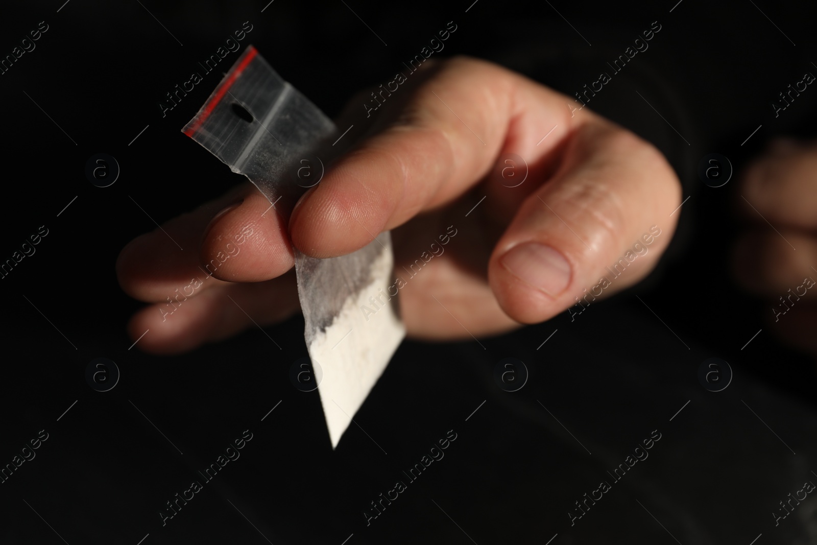 Photo of Drug addiction. Man with plastic bag of cocaine on dark background, closeup