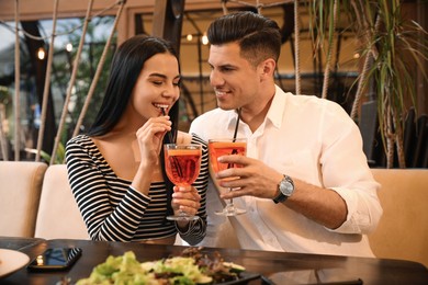 Photo of Lovely couple with Aperol spritz cocktails resting together at restaurant