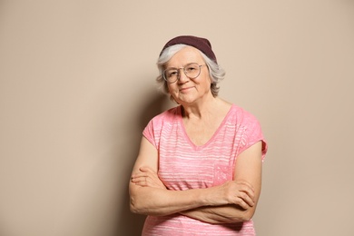 Portrait of elderly woman in hipster outfit on color background