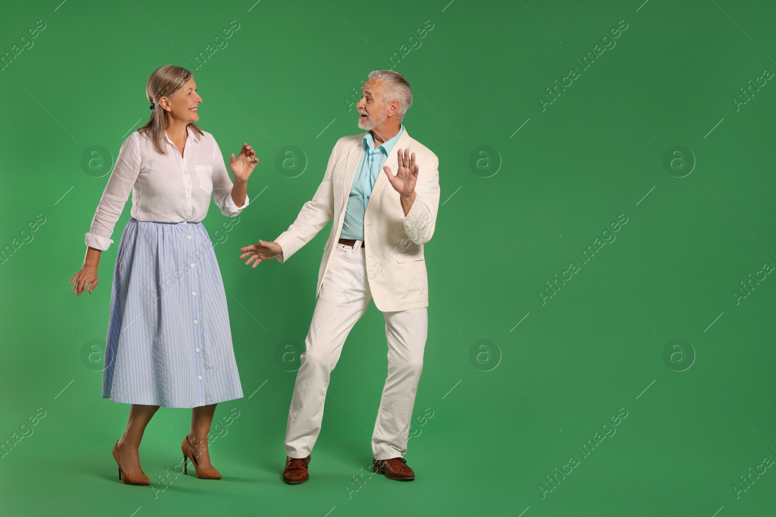 Photo of Senior couple dancing together on green background, space for text