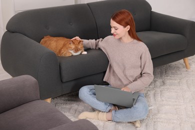 Woman stroking cat while working with laptop at home