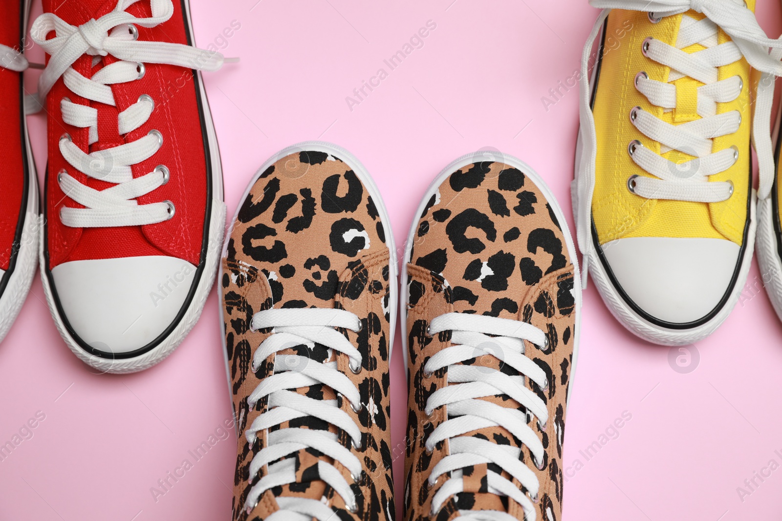 Photo of Different classic old school sneakers on pink background, flat lay