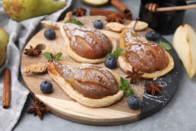 Photo of Delicious pears baked in puff pastry with powdered sugar served on grey table, closeup