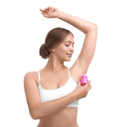 Young woman applying deodorant to armpit on white background