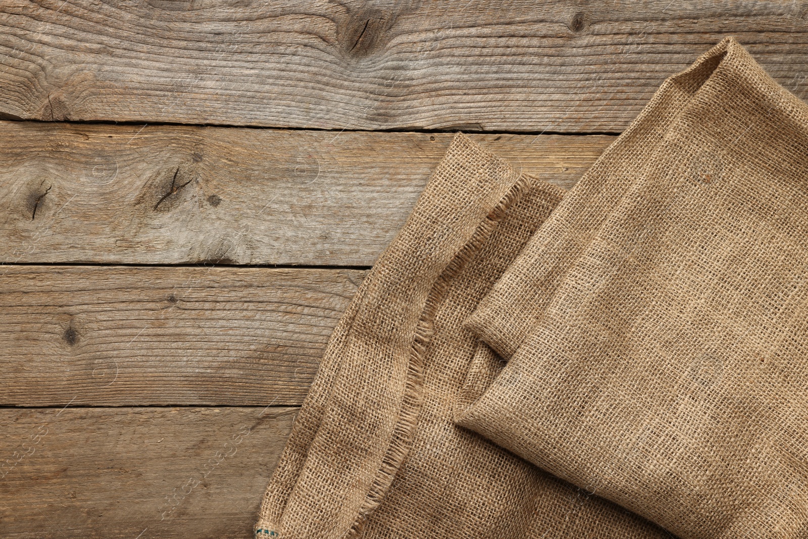 Photo of Burlap fabric on wooden table, top view. Space for text