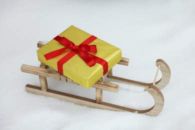 Wooden sleigh with gift box on snow outdoors