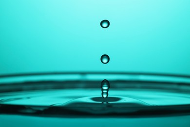 Photo of Splash of clear water with drops on turquoise background, closeup