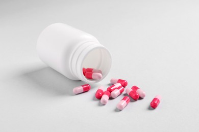 Photo of Medical bottle and pink pills on white background