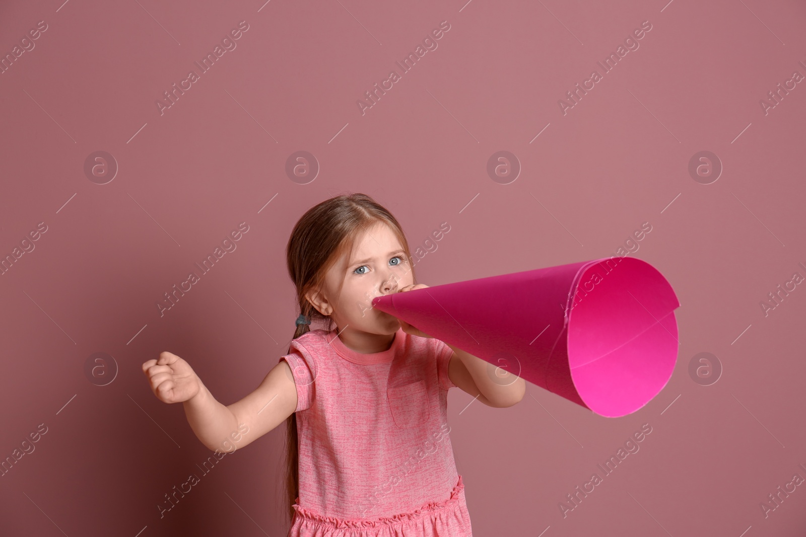 Photo of Adorable little girl with paper megaphone on color background